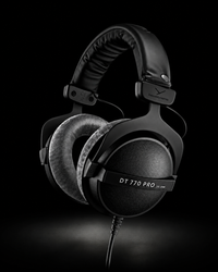 Black over-ear headphones with plush ear cushions and a padded headband, shown at an angle on a dark studio background. The earcup displays the text 'DT 770 PRO' and the brand logo.