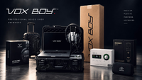 VOX BOY voice-over kit arranged on a dark studio surface, including a laptop in an open hard case, headphones, carrying case, audio device, boxes, and accessories. Large VOX BOY branding is visible on the laptop, case, and boxes.