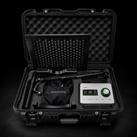 An open black hard carrying case on a black background, containing a silver and black audio device with a digital display and green control dial, along with a black pouch labeled beyerdynamic and a foam-lined interior.